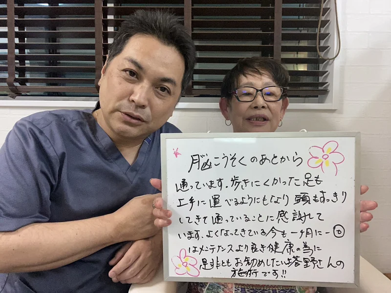 「脳こうそくのあとから通っています。歩きにくかった足も上手に運べるようにもなり頭もすっきりしてきて通っていることに感謝しています」と書かれたボードを、女性のお客様と院長が一緒に持っているところ
